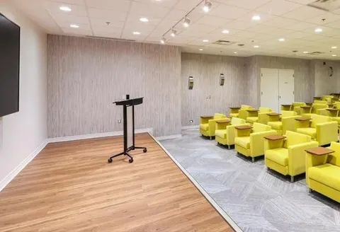 Theatre with rows of yellow armchairs beside a stage.
