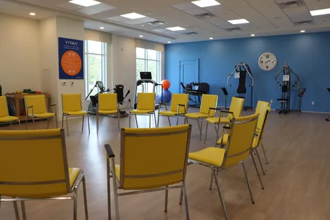 Fitness room with yellow chairs, exercise machines, a treadmill and exercise balls