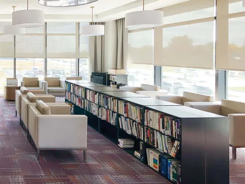 Library with low bookcases and armchairs beside large windows