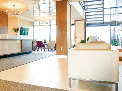 Lobby with a reception desk, armchairs and a glass-sided staircase