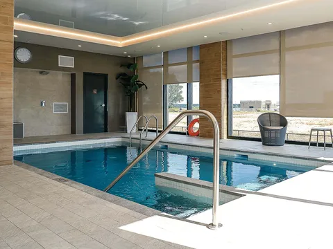 Indoor swimming pool with handrails, tiled surround and floor-to-ceiling windows