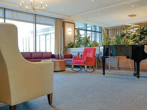 Lounge with sofas, armchairs, a grand piano and indoor plants