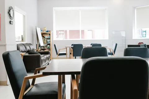 Room with tables, upholstered chairs and large windows