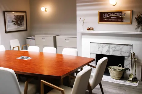 Large wooden table with chairs beside a white fireplace