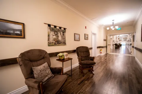 Hallway with two recliners, framed artwork and doors along the walls