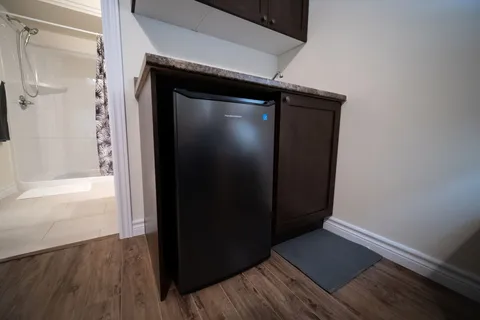 Compact kitchenette with dark cabinets and a refrigerator beside a bathroom