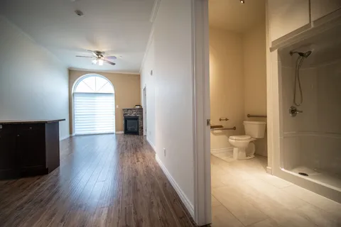 Unfurnished room beside a bathroom with a shower, toilet and tiled floor