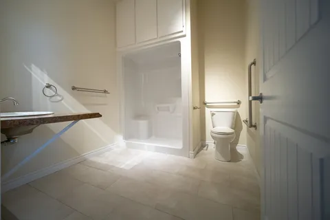 Bathroom with a walk-in shower, toilet, countertop sink and tiled floor