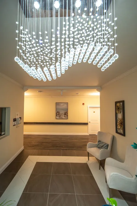 Waiting area with upholstered chairs beneath a hanging crystal light fixture