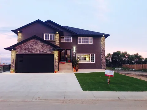 Two-storey residence with a stone-fronted garage, front steps and lawn.