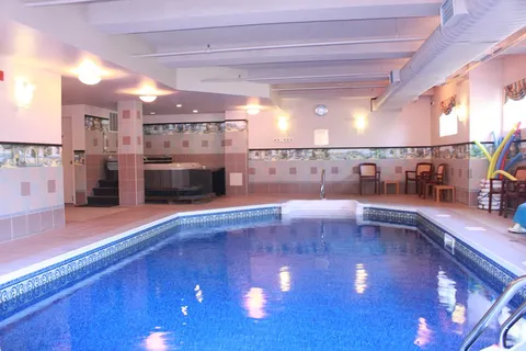 Indoor swimming pool with blue water, tiled walls and poolside chairs