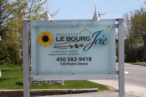 Residence sign on posts beside trees and a road