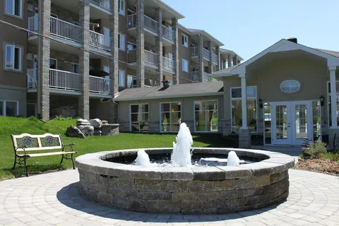 Stone fountain with water jets in a paved courtyard beside the residence