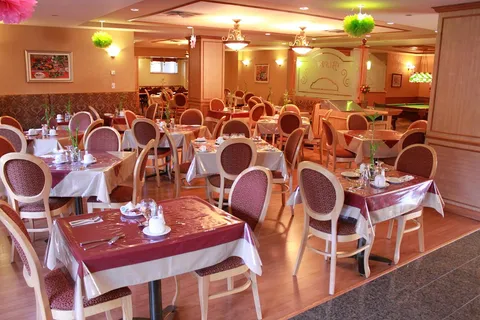 Dining room with red chairs, set tables, warm lighting and flower decorations
