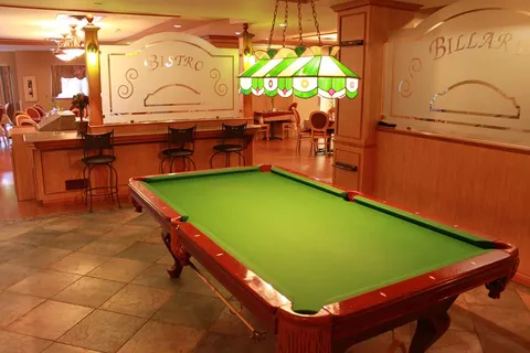 Billiard room with a green pool table, pendant light and a counter with stools