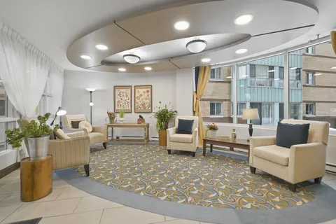 Curved sitting area with cream armchairs, plants and large windows