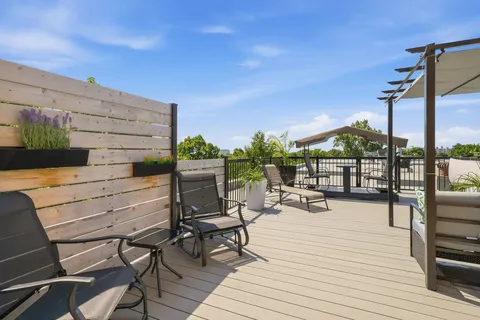 Wooden terrace with outdoor chairs, planters and shade structures
