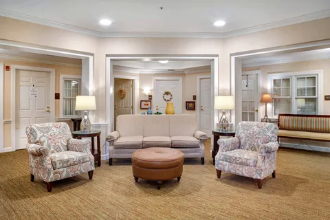 Living room with sofas, armchairs, a piano and an ottoman.