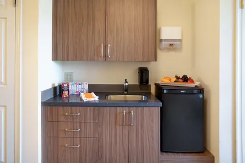 Suite kitchenette with a sink, wooden cupboards and a refrigerator.