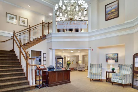 Lobby with a reception desk, staircase, chandelier and seating.