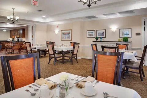 Dining room with set tables, wooden chairs and a service counter.