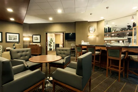 Pub lounge with armchairs, tables and a bar counter.