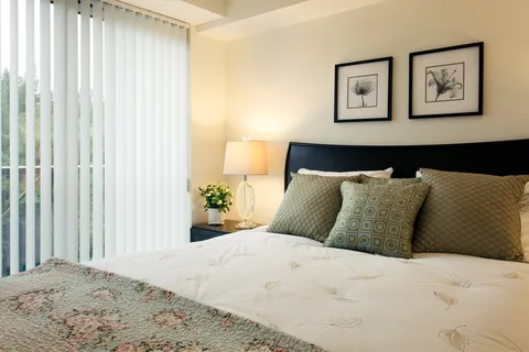 Bedroom with a bed, bedside table and tall windows.