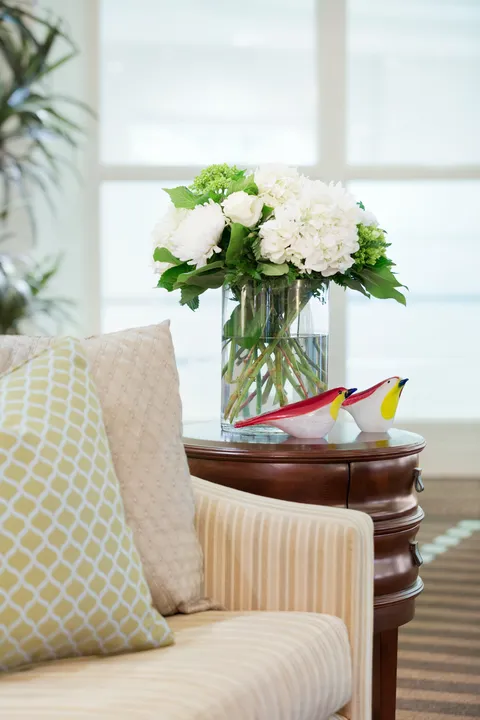 Lobby seating with a side table and flowers beside a window.