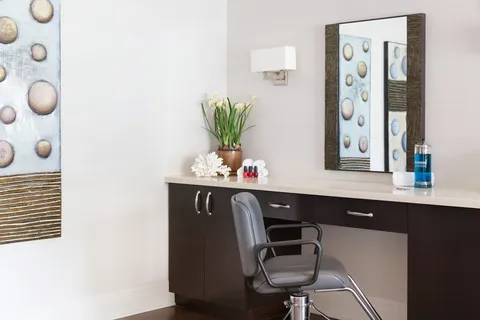 Salon styling chair beside a counter and mirror.