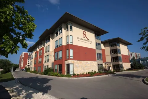 Multi-storey building with beige and red walls beside a driveway