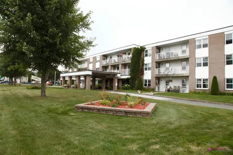 Three-storey residence with balconies, a lawn and a flower bed.
