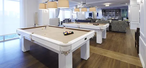 Games room with white pool tables and lounge seating