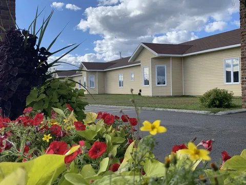 Single-storey residence with flower beds beside the driveway.