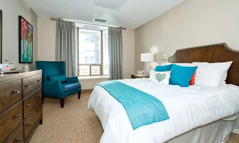 Suite bedroom with a bed, armchair and dresser.