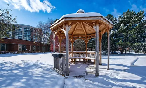 Wooden gazebo on snow-covered grounds.