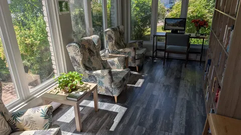 Armchairs beside tall windows, a small table and a bookcase