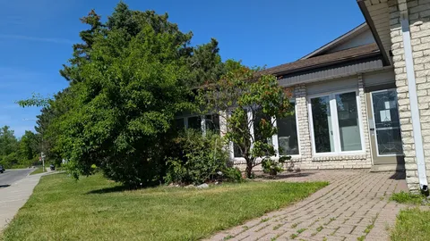 White brick building beside a paved path, grass and leafy trees