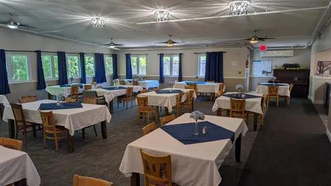 Dining tables with white tablecloths and blue overlays beside large windows