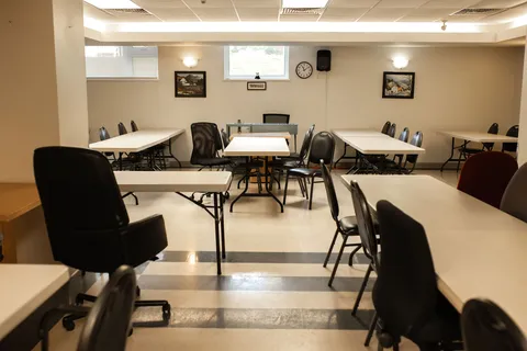 Room with white tables, black chairs and framed landscape pictures