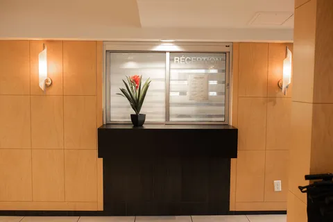 Reception counter beneath a glass window in a wood-panelled wall