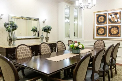 Dining table and upholstered chairs beside a large wall mirror