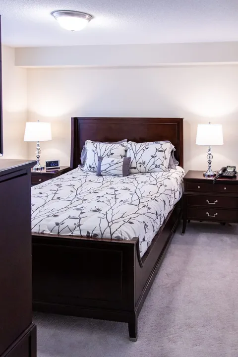 Bedroom with a patterned bed cover, bedside tables and matching lamps