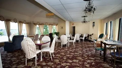 Activity hall with tables, chairs, chandeliers and curtained windows.
