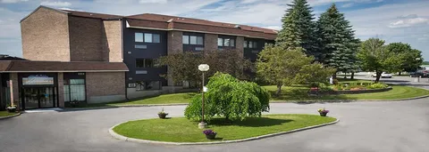 Front entrance driveway with a landscaped island and mature trees.