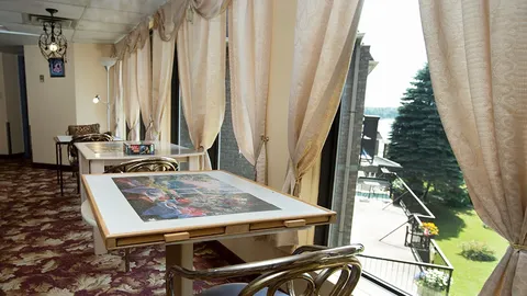 Sunroom with puzzle tables beside windows overlooking the river.