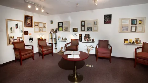 Sitting room with armchairs, side tables and framed pictures.