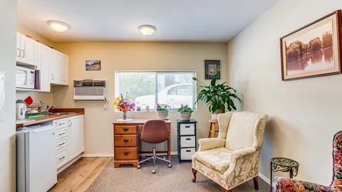 Suite living area with an armchair, desk and kitchenette.
