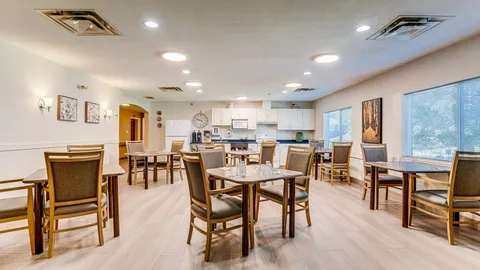 Dining room with wooden tables and chairs beneath ceiling lights.
