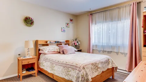 Suite bedroom with a double bed beside a curtained window.