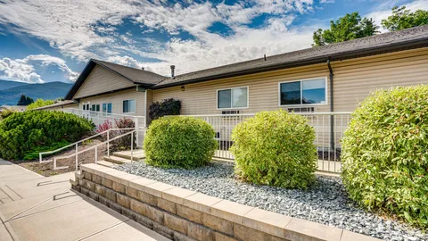 Residence exterior with a ramp, shrubs and raised stone garden beds.